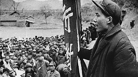Man with banner speaks to crowd of Chinese people