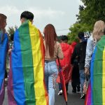 people marching with rainbow flags draped over themselves