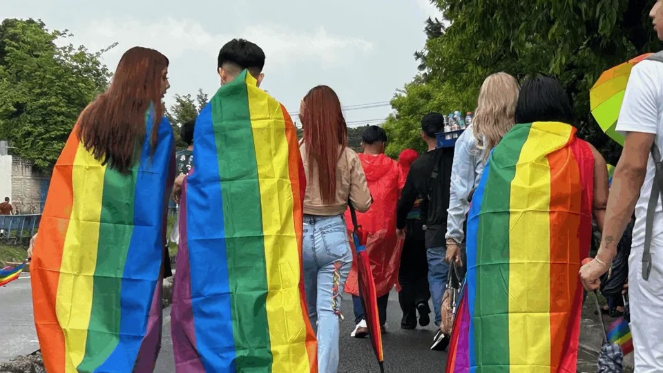 people marching with rainbow flags draped over themselves