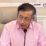 Colombian President Gustavo Petro sits at microphone in front of Colombian flag