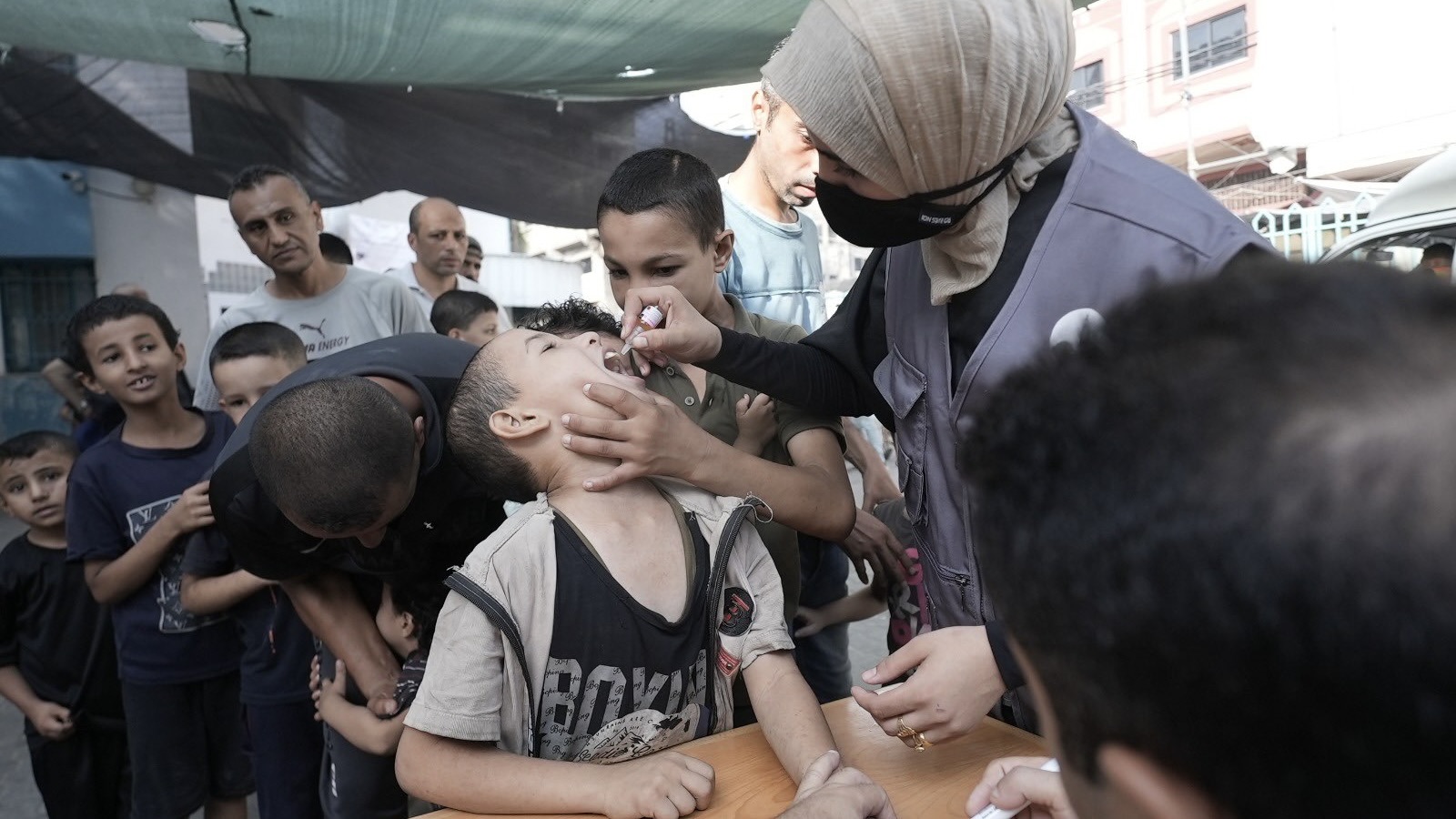 nurse gives vaccine to child in Gaza