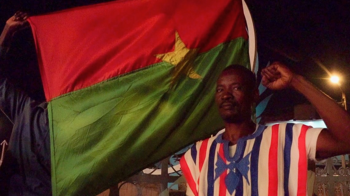 Man raised the fist in front of flag of Burkina Faso