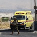 Israeli soldiers in front of yellow ambulance truck
