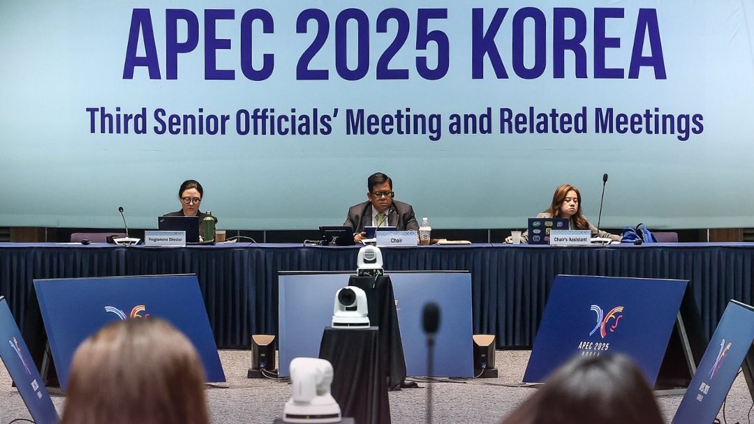 Officials sit in front of APEC 2025 Banner