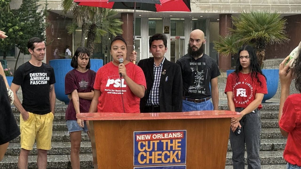 Grassroots organizers speak at podium under umbrellas in the rain